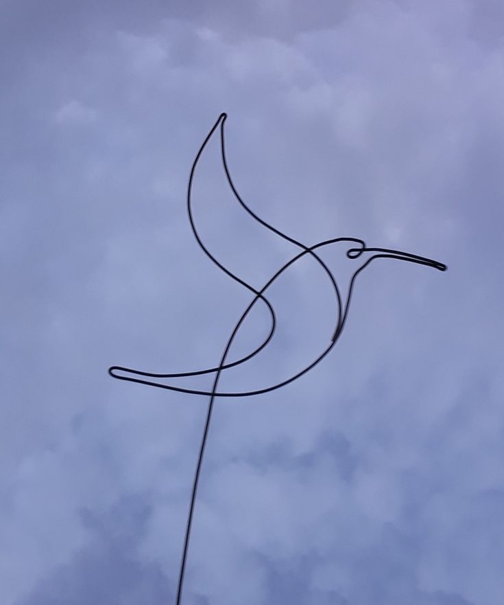 a bird shaped kite flying in the sky on a cloudy day with blue skies and white clouds