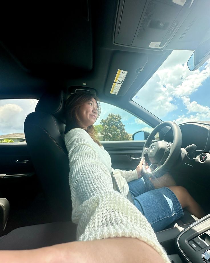 a woman sitting in the driver's seat of a car with her feet on the steering wheel