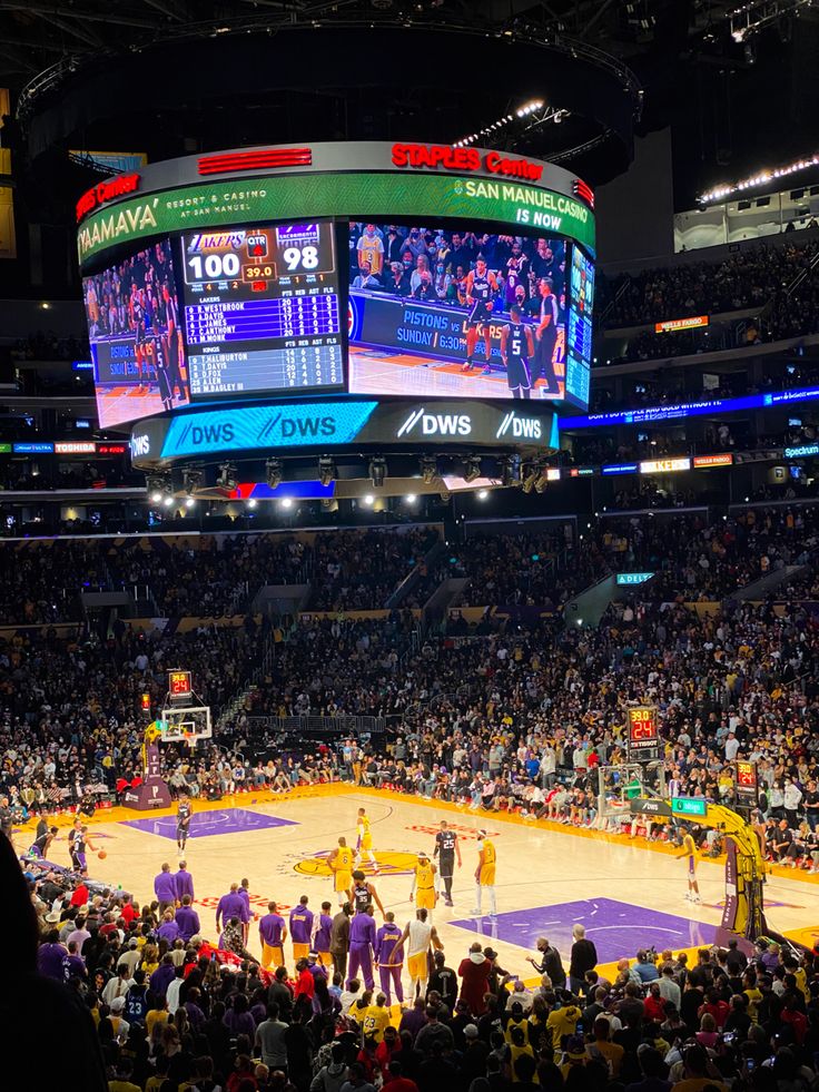 a basketball game is being played in an arena with people watching from the sidelines