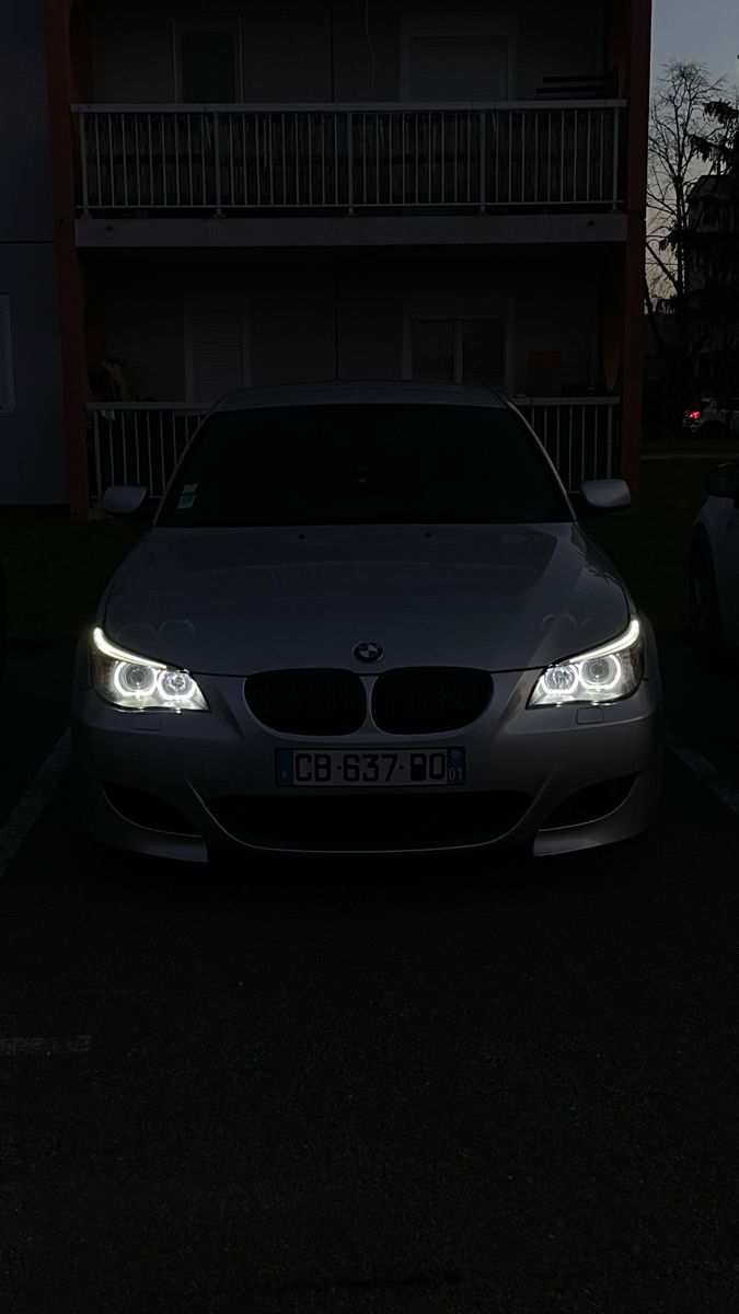 a car parked in front of a building at night with its lights on and it's headlight turned on