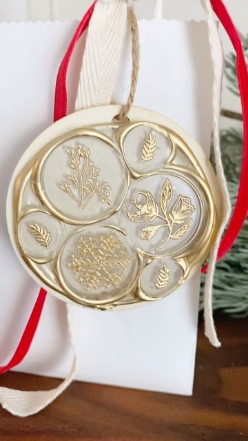 an ornament hanging from a red ribbon on top of a white paper bag