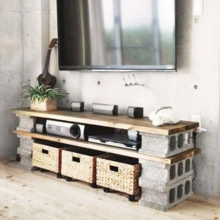 a flat screen tv mounted to the side of a wall next to baskets and plants