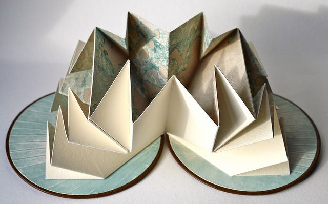 three folded paper sculptures on a plate, one is blue and the other is white