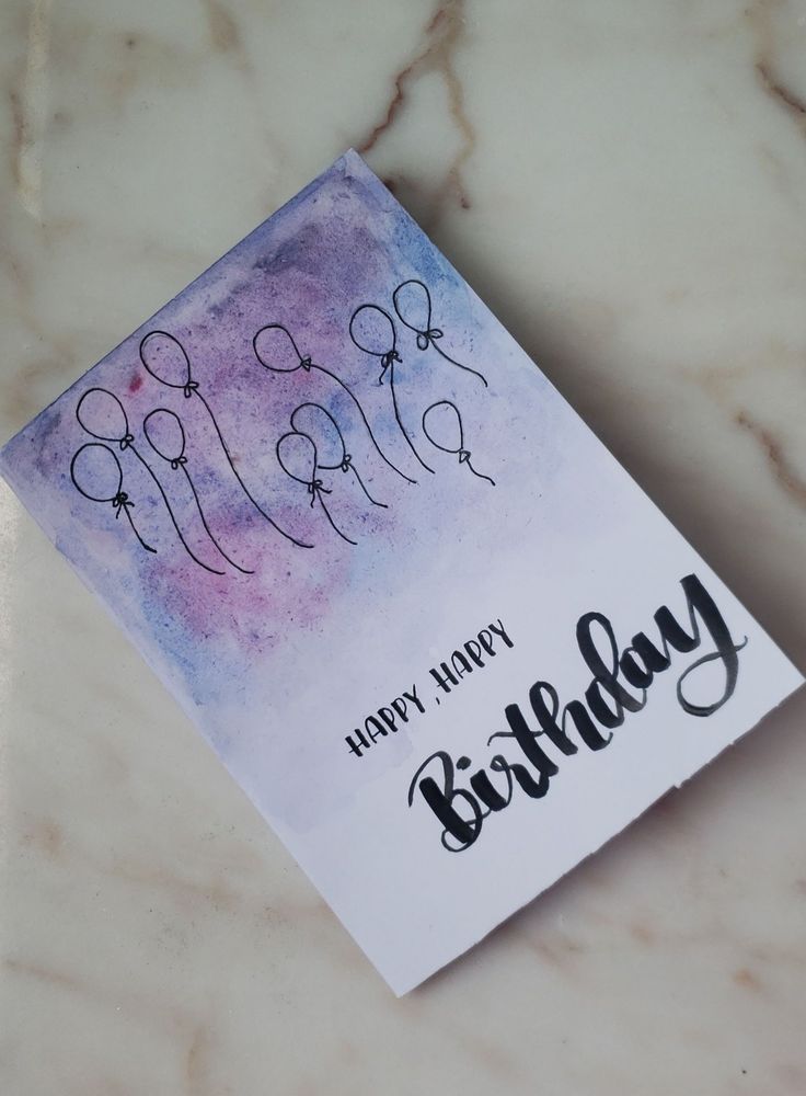 a happy birthday card sitting on top of a marble table with the word happy written in cursive writing