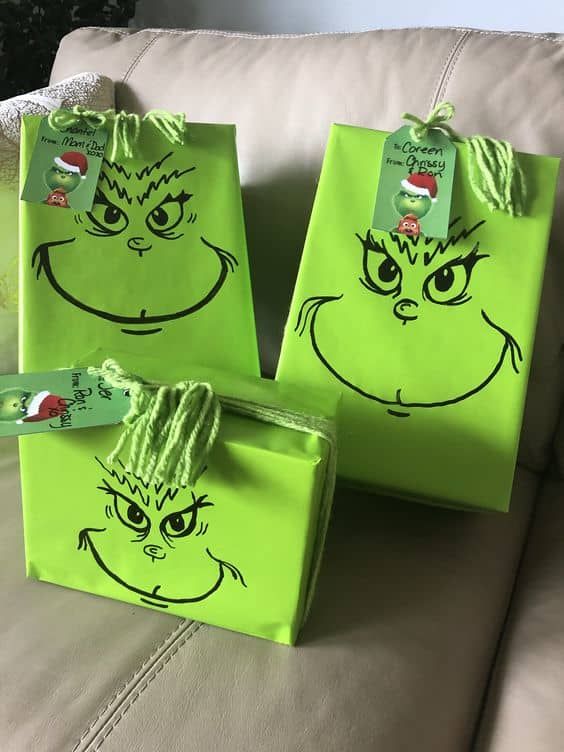 three green bags with faces drawn on them sitting on a couch next to each other