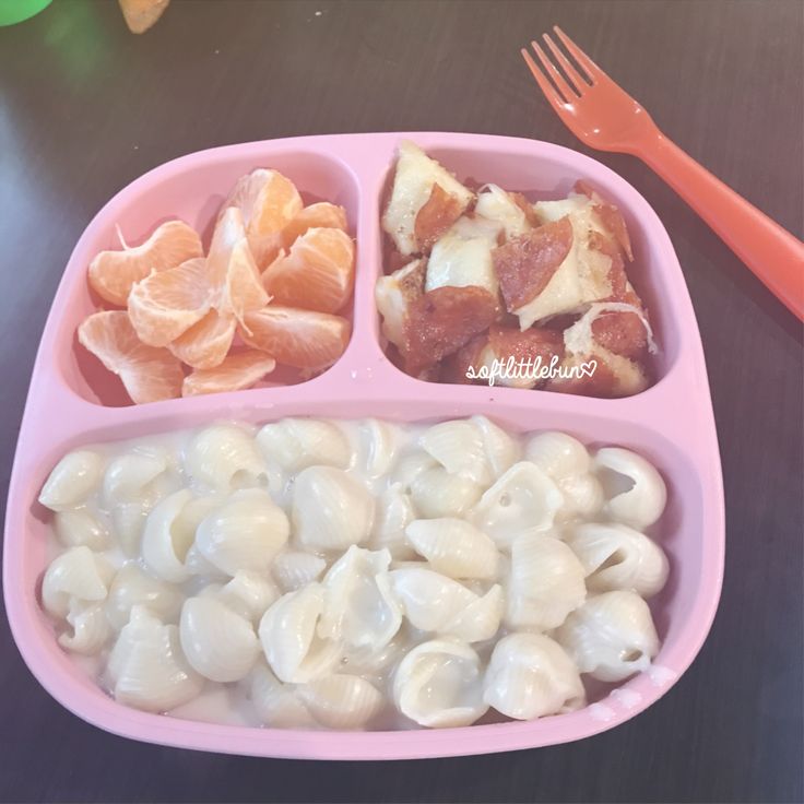 a pink plate filled with pasta, meat and veggies next to a fork