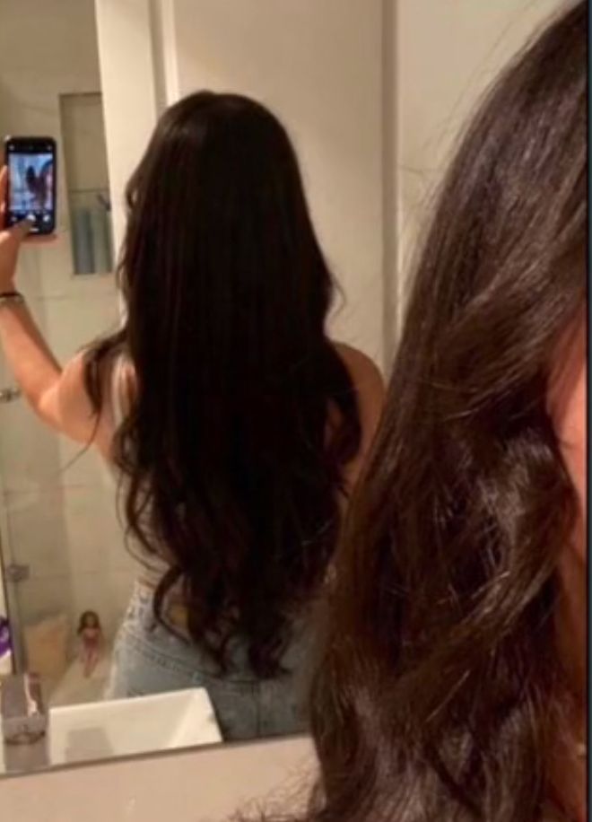 a woman taking a selfie in front of a bathroom mirror with her cell phone