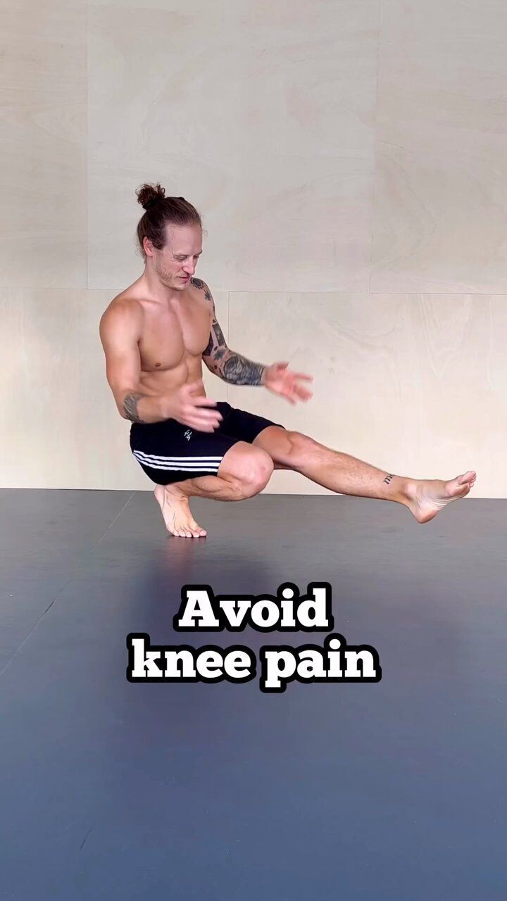 a shirtless man is sitting on the floor with his leg up and arms spread out