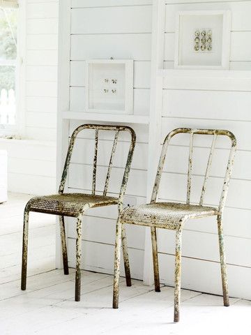 two chairs sitting next to each other in front of a white wall and window with shutters