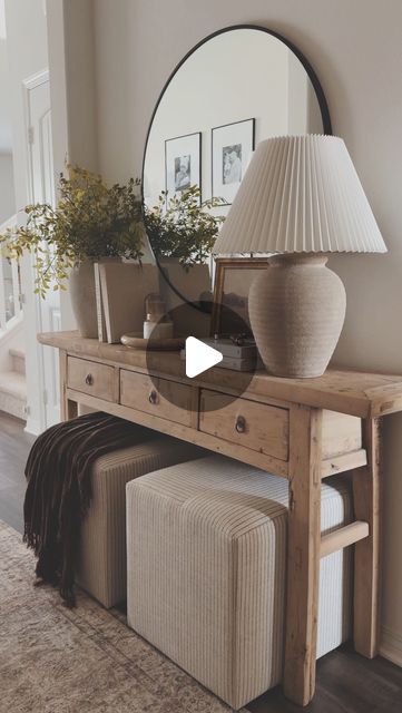 a table with a mirror, lamp and stools on it in a living room