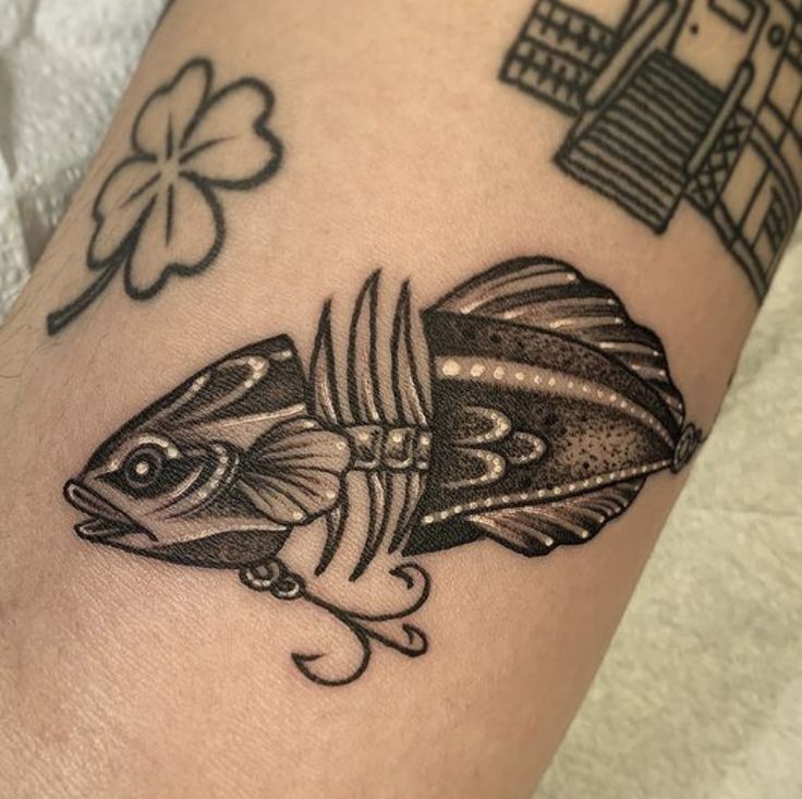 a black and white photo of a fish on someone's leg with clovers in the background