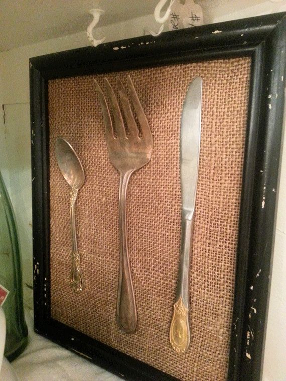 two forks and spoons are placed in a shadow box with burlap on the wall