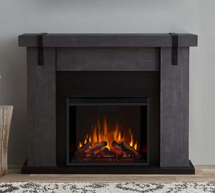 an electric fireplace in a living room with a clock on the wall above it and a vase next to it