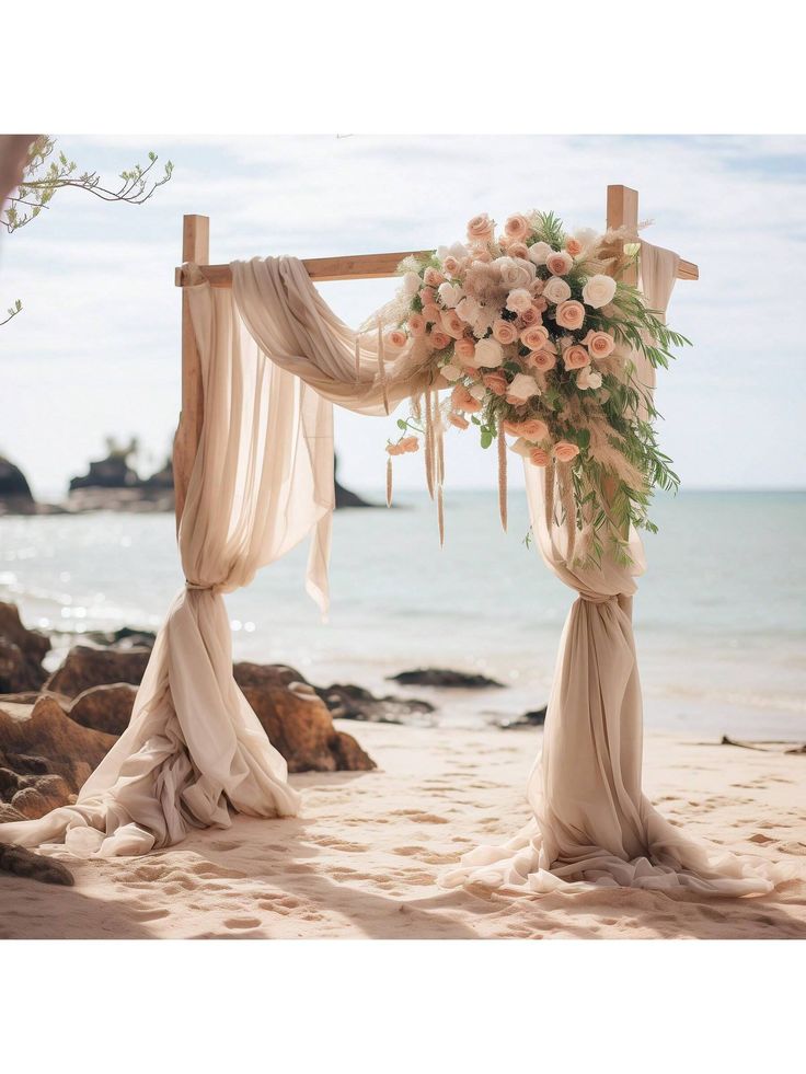 an outdoor wedding setup on the beach with flowers and draping draped over it