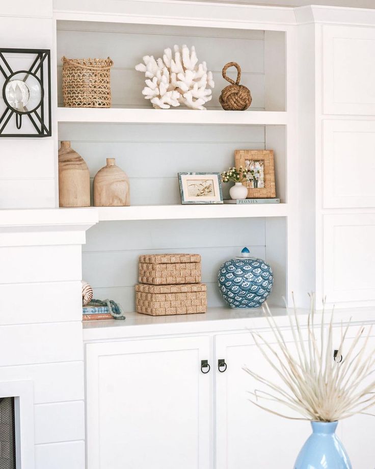 a white shelf with baskets and vases on it