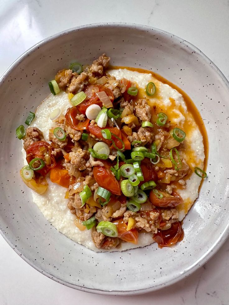 a white plate topped with rice covered in meat and veggies next to a fork