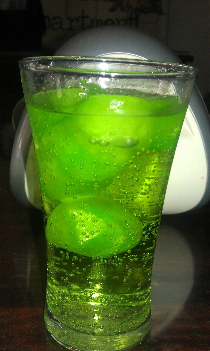 a glass filled with green liquid on top of a table