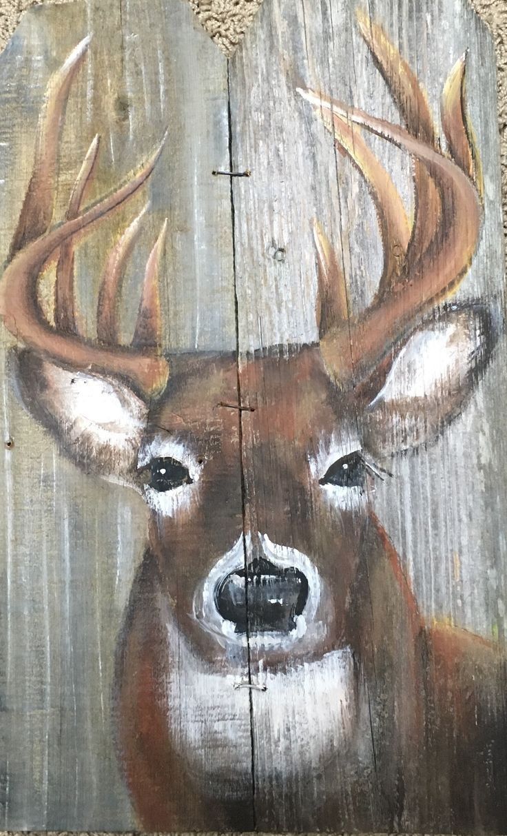 a painting of a deer with antlers on it's head is painted on a piece of wood