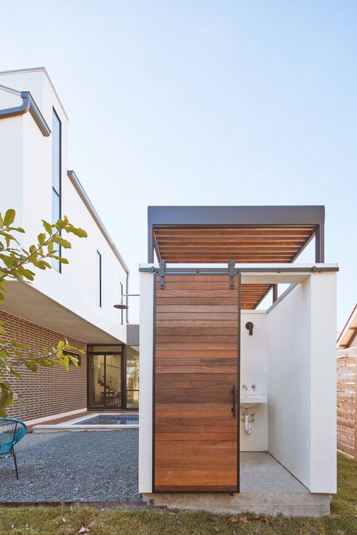 a modern house with a wooden door and white walls on the outside, surrounded by grass