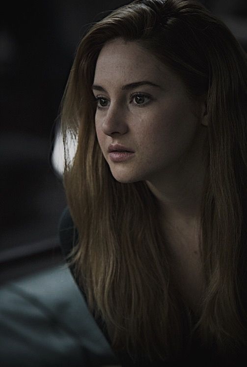 a woman with long hair sitting in a car looking off into the distance while staring at something