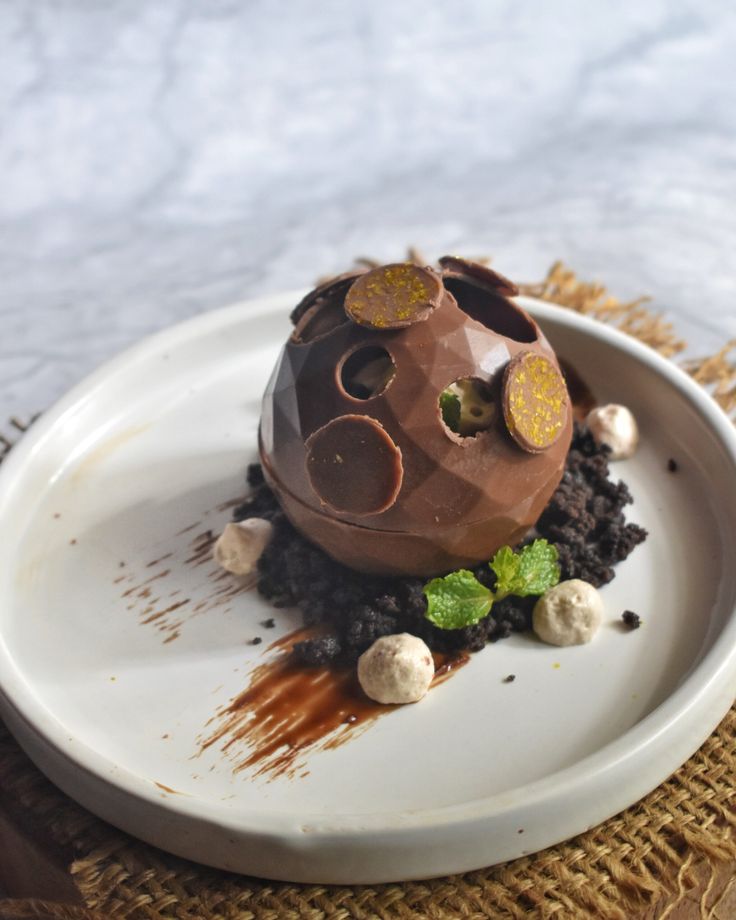 a chocolate dessert on a white plate topped with nuts