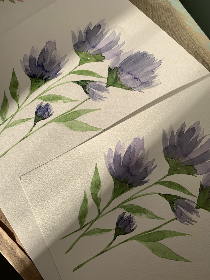 some watercolors are being used to paint flowers and leaves on white cards with green stems