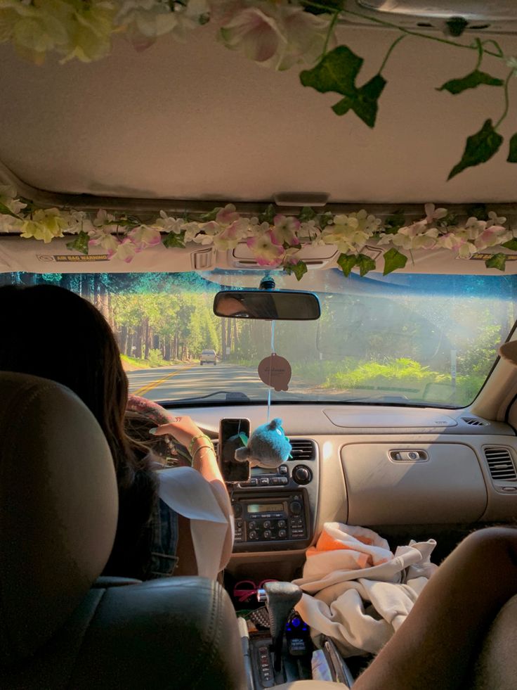 two people sitting in the back seat of a car with flowers hanging from the ceiling