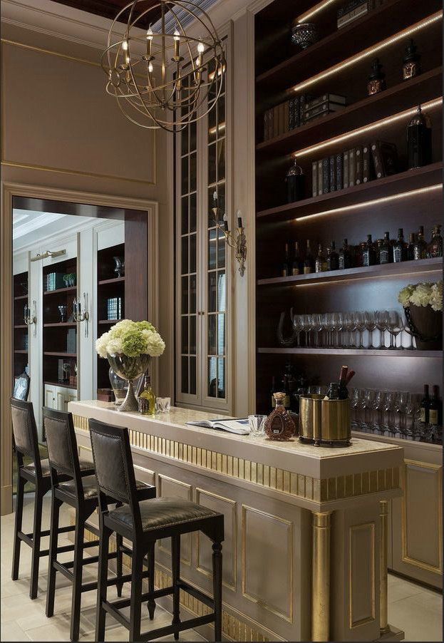 a bar with several bottles and glasses on top of it in front of an open bookcase