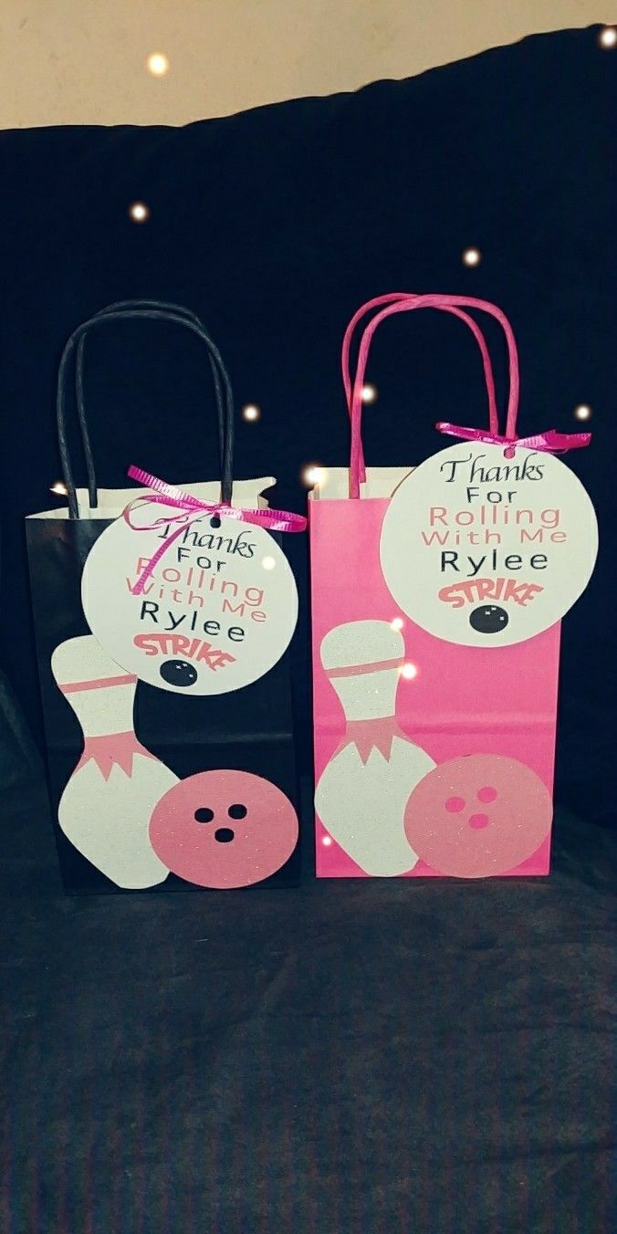 two pink and black paper bags sitting on top of a bed next to each other