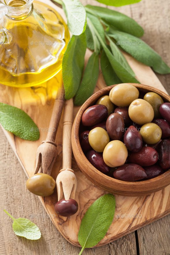 olives in a wooden bowl next to an olive oil bottle