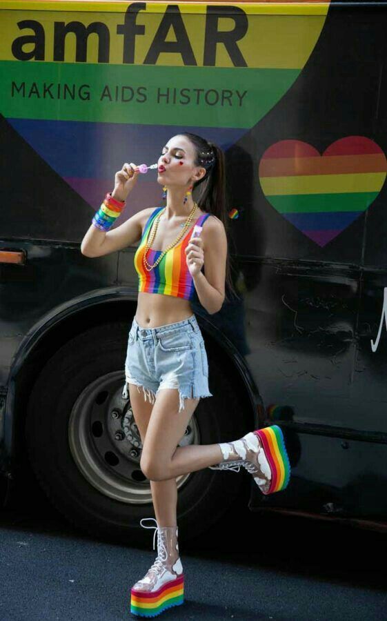 a woman in shorts and rainbow socks standing next to a bus with her mouth open