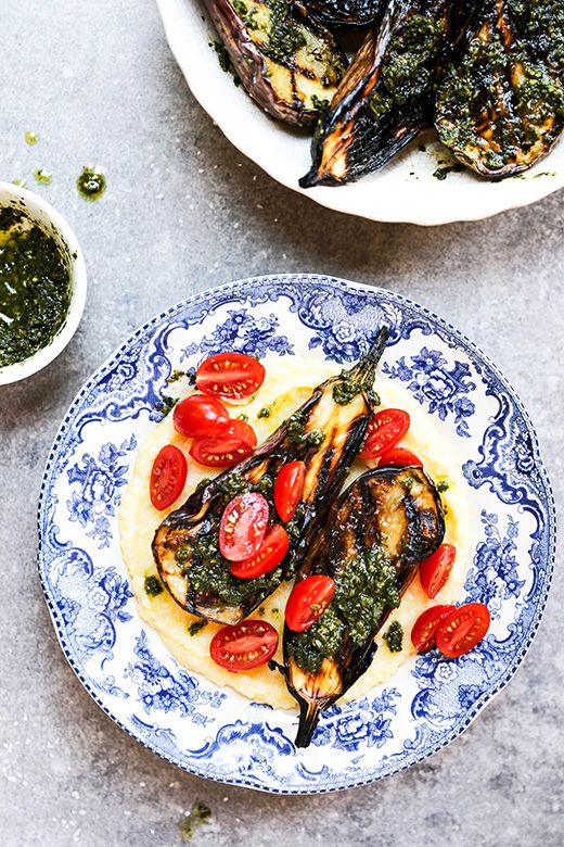 two plates filled with food on top of a white and blue tablecloth next to bowls of pesto