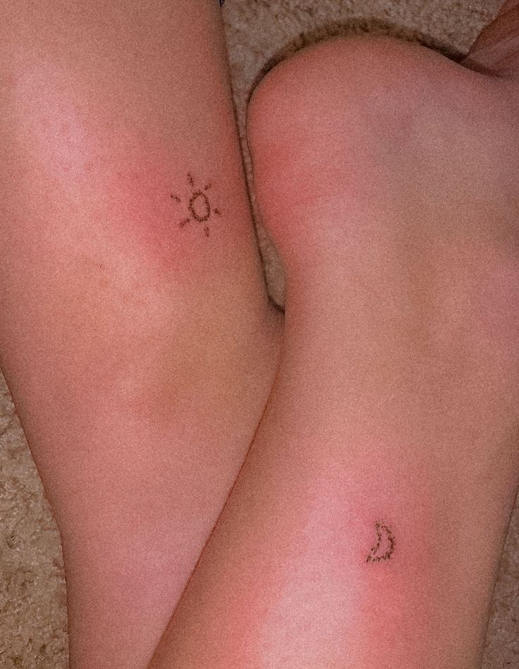 two women's legs with small tattoos on them