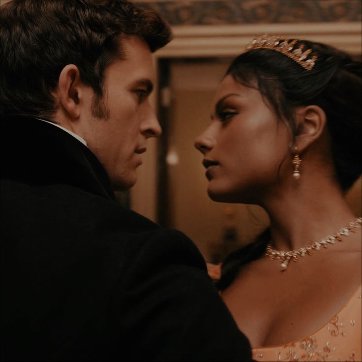 a man in a tuxedo standing next to a woman wearing a tiara