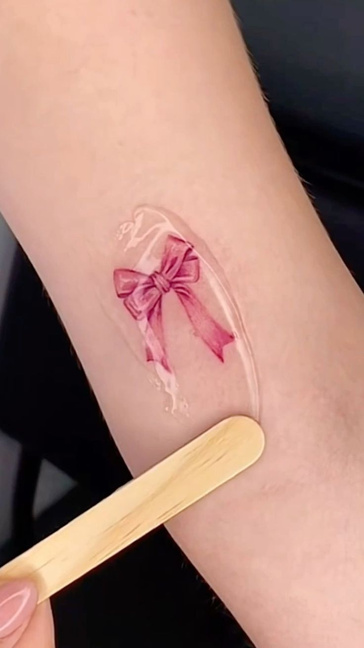 a woman with a pink bow on her arm holding a toothbrush in her hand