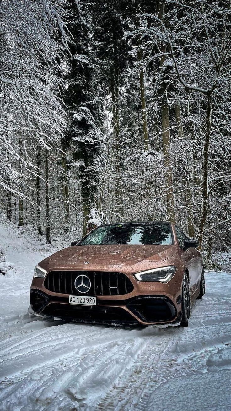 the mercedes amg gt is driving on a snowy road with trees in the background