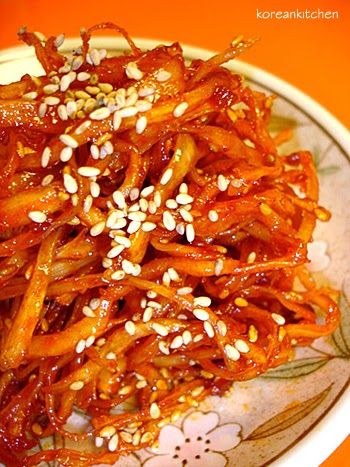 a plate full of food with sesame seeds and sauce on the side, sitting on an orange tablecloth