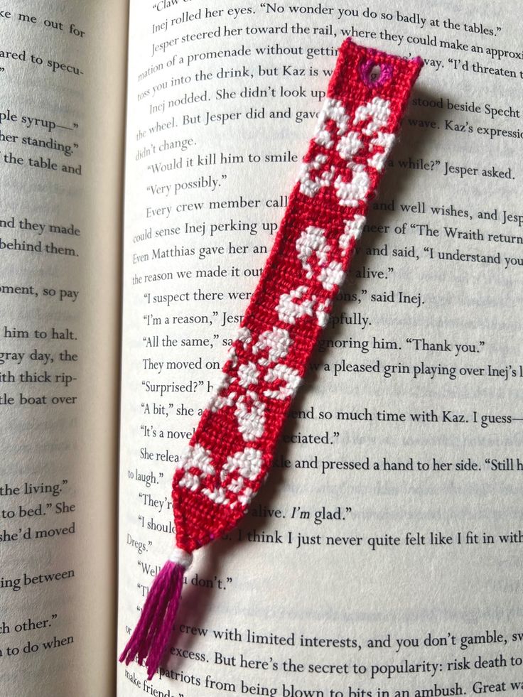 an open book with a red and white beaded bracelet on it's cover