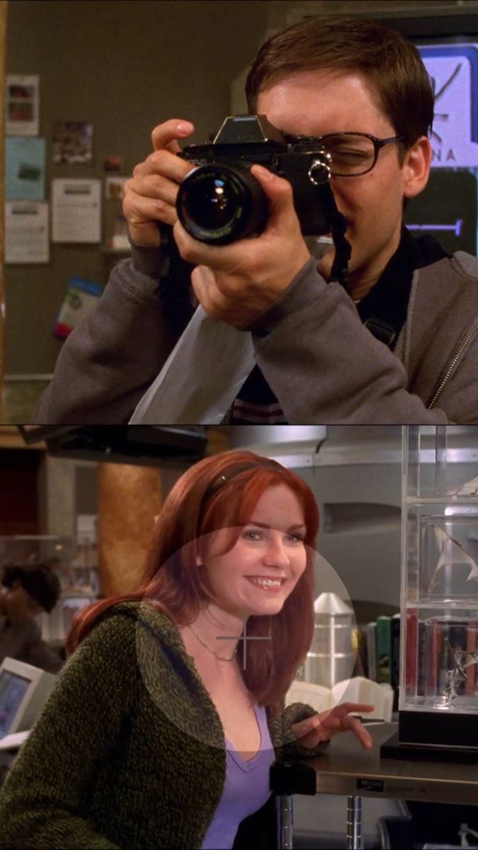 two people taking pictures with their cameras in the same room, one woman is smiling and the other man is holding a camera