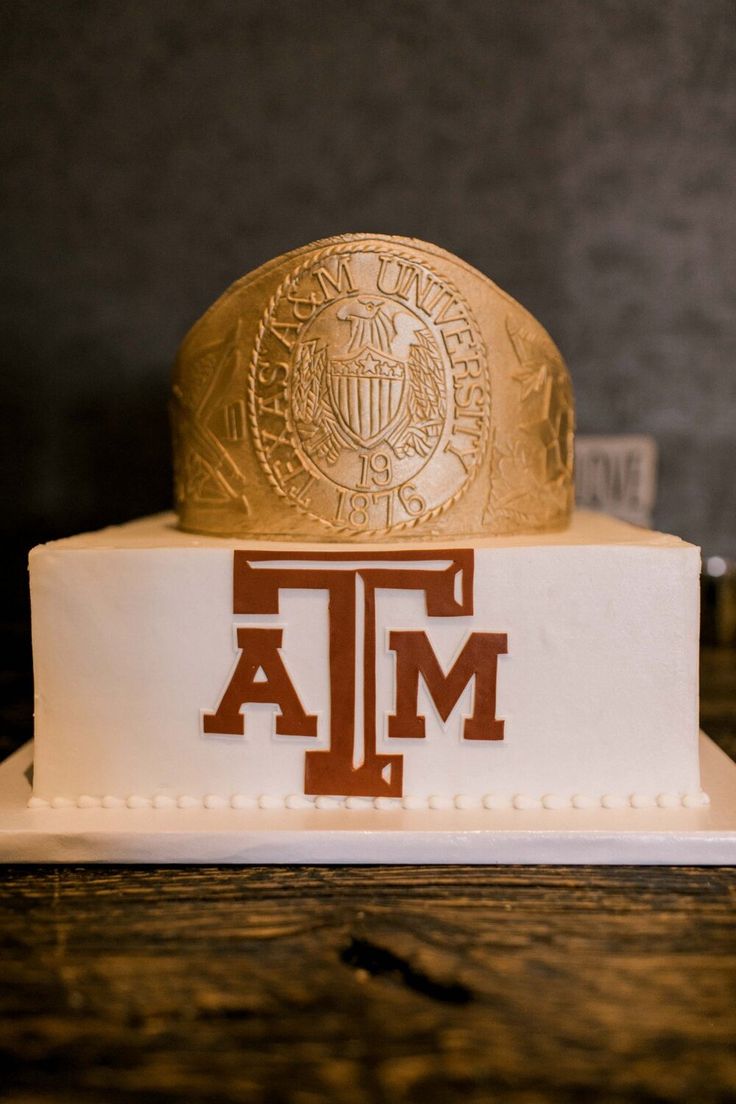 two tiered cake with the letters t and m on it's side, sitting on top of a wooden table