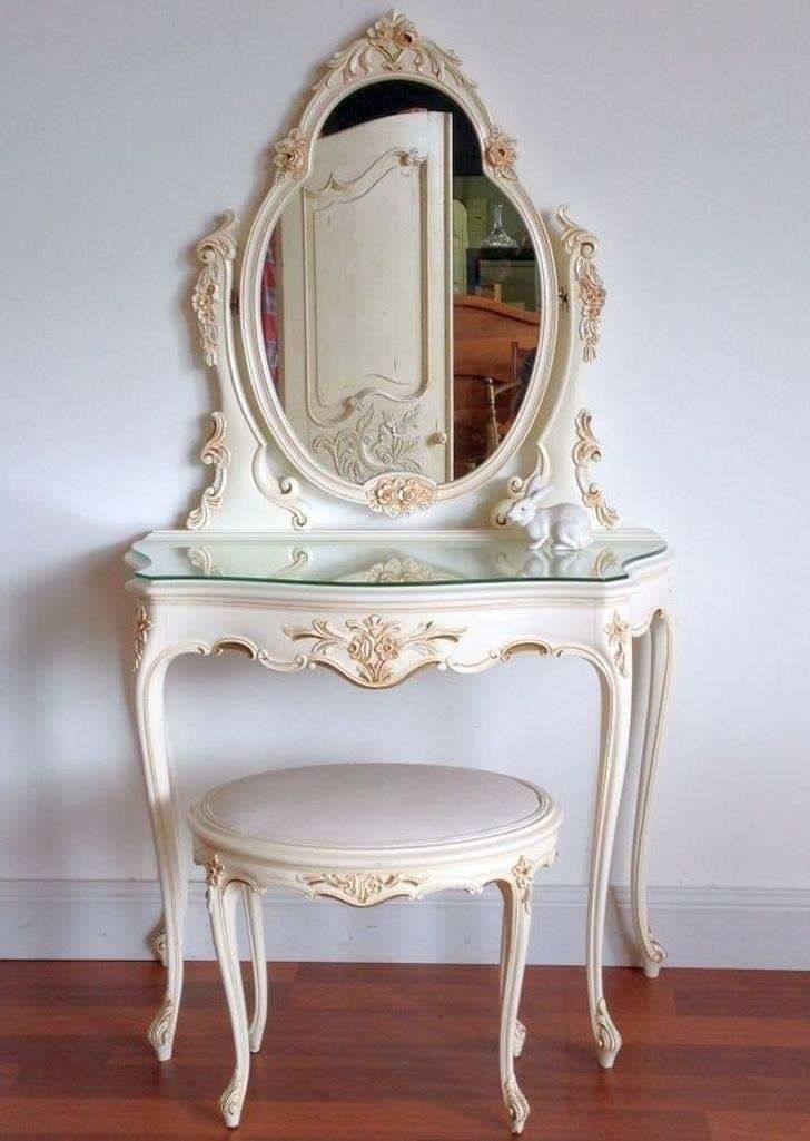 a white vanity with a mirror and stool in front of it on a hard wood floor