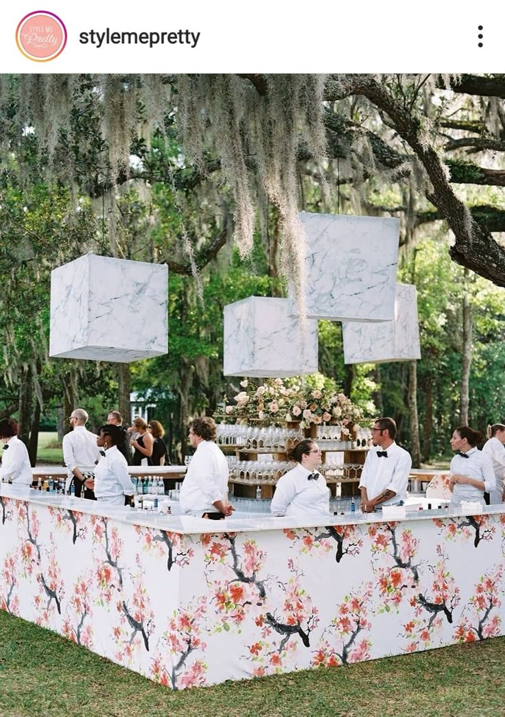 people are sitting at a buffet table with flowers on it and hanging from the ceiling