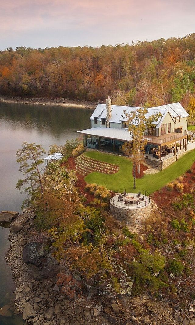 an aerial view of a house on the edge of a body of water surrounded by trees