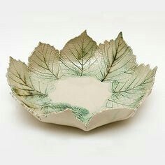 a green and white bowl with leaves on it