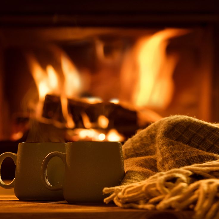 two coffee mugs sitting next to each other on a table near a fire place