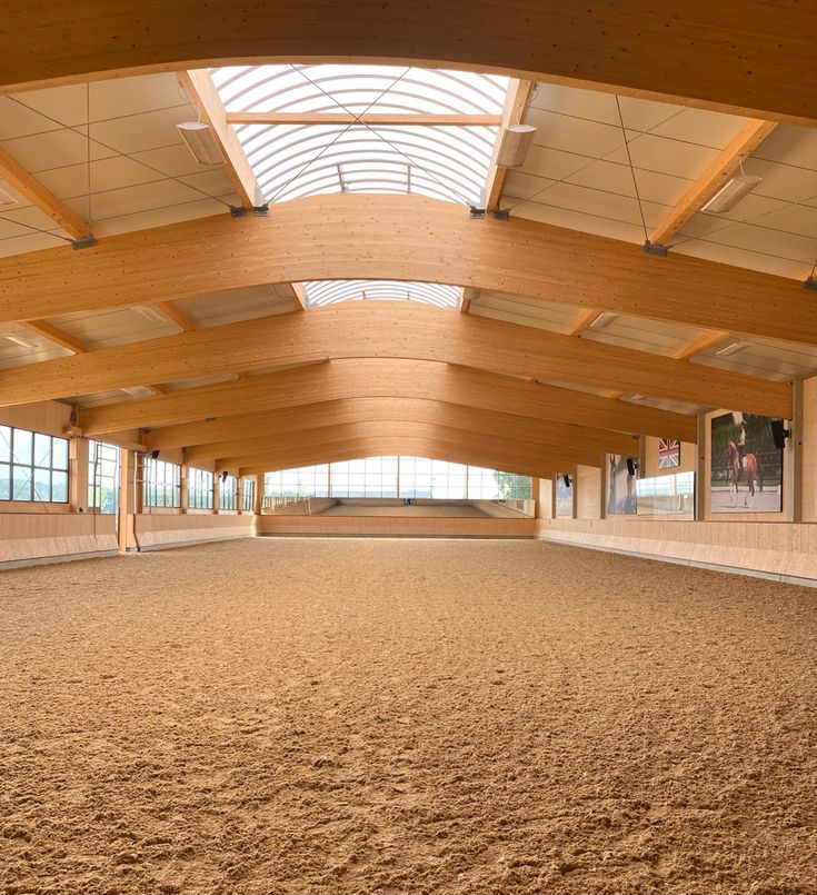 the inside of an indoor arena with lots of sand and wooden beams on the ceiling