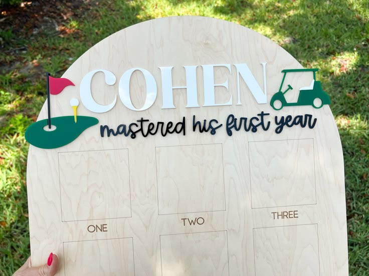 a person holding up a wooden sign that says cohen, master and first year