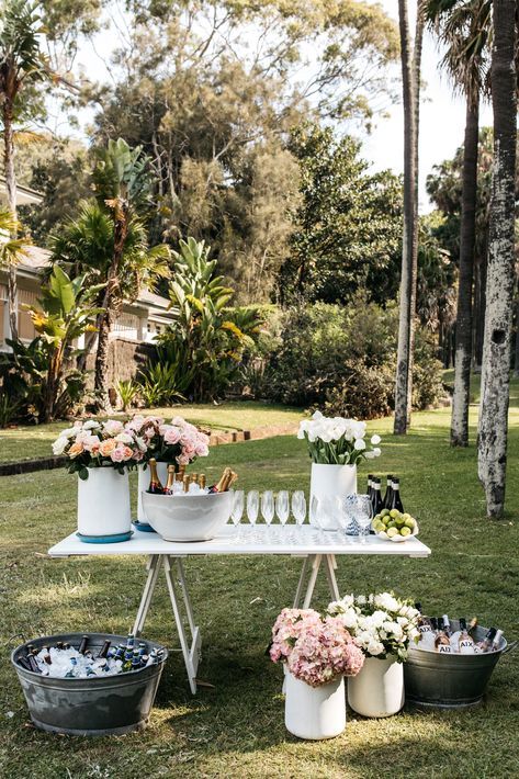 a table with flowers and wine glasses on it in the middle of grass near palm trees