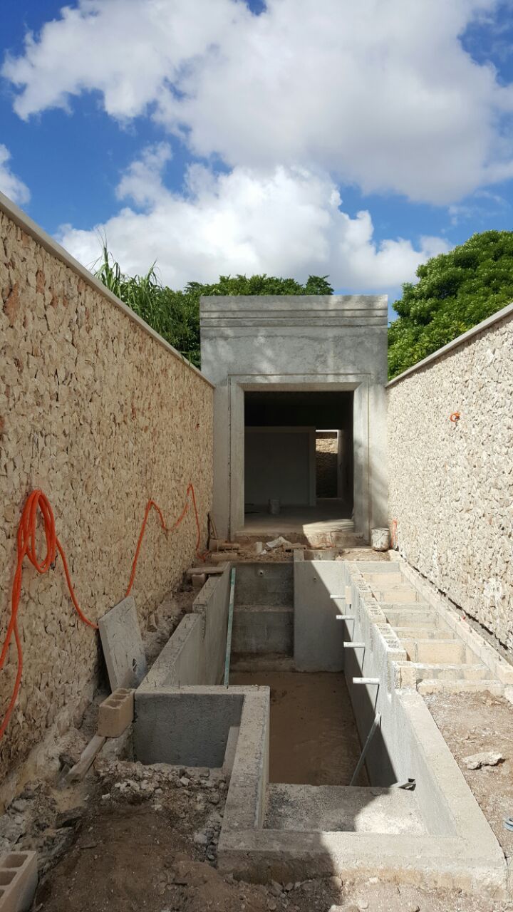 an unfinished building with concrete walls and steps leading up to the entrance area, in front of a cloudy blue sky