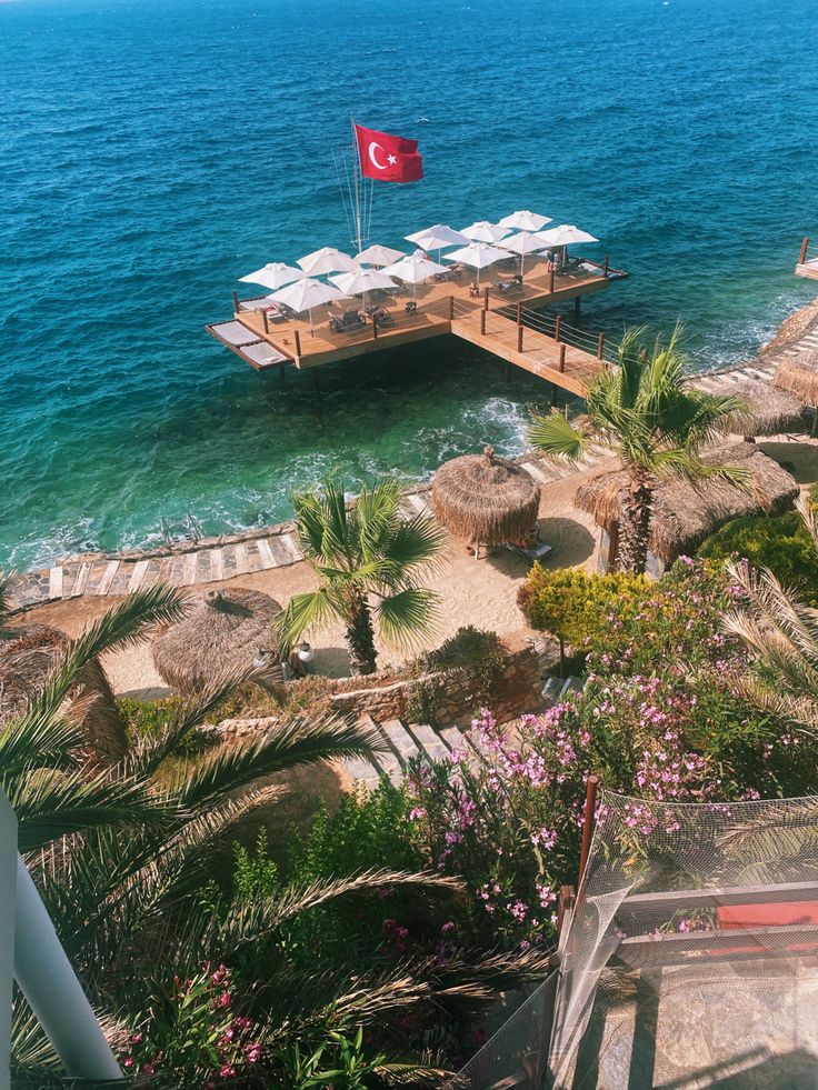 a dock with chairs and umbrellas in the water next to some palm trees,